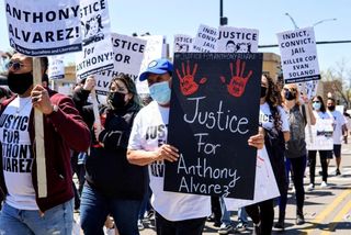 Marchingp protesters carrying signs reading "Justice for Anthony Alvarez."