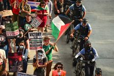 protester with Palestinian flag marches alongside Chicago police officers with bicycles