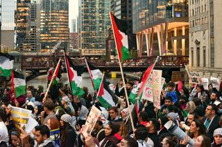 A protest march for Palestine crosses over a bridge; Chicago river, skyscrapers and CTA train in the background.